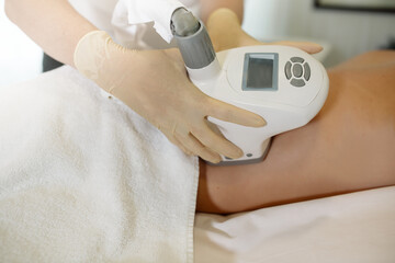 The nurse performs the manipulations with the lymphatic drainage apparatus on the woman's abdomen, doing anti-cellulite massage