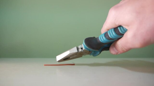 the master cuts a metal wire with pliers