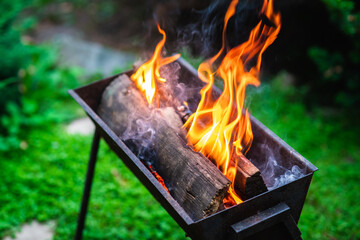 Old braizer with burning firewood on the backyard. Selective focus. Shallow depth of field.