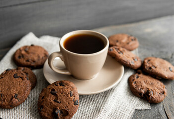 Coffee cup with cookies on wooden table background. Mug of black coffee with chocolate cookies. Fresh coffee beans.