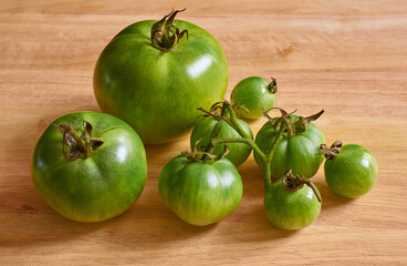 Green unripe tomatoes on a wooden background.