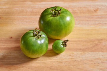Green unripe tomatoes on a wooden background.