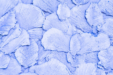 The background is lilac. Abstract drawing made of concrete, made on the wall with special tools. The decorative surface in the form of petals is made of cement. Light purple pattern.