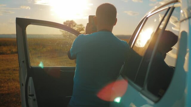 A man takes a photo on his phone while traveling in his car.