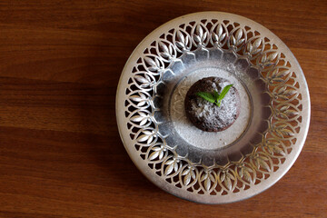 Chocolate muffin on a silver plate top view. Dessert with a leaf of mint.