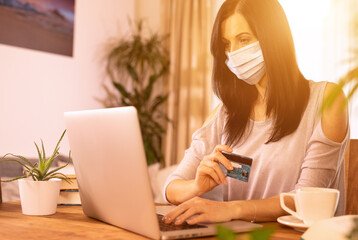 Woman is holding credit card and using laptop computer. Online shopping concept.