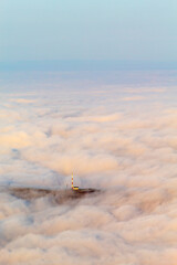 Una antena de comunicaciones asoma entre un inmenso mar de nubes.