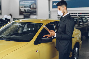 Man car dealer wearing protective medical mask on his working place