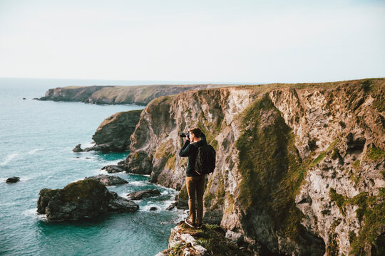 Male photographer on scenic ocean cliff, Bedruthan Steps, Cornwall, UK

