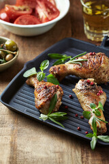 Spicy chicken drumsticks with fresh herbs. Close up.