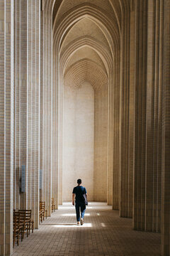 Young man walking along cloister, Grundtvigs Church, Copenhagen, Denmark
