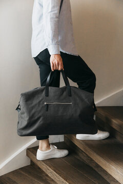 Man with duffel bag climbing wood stairs
