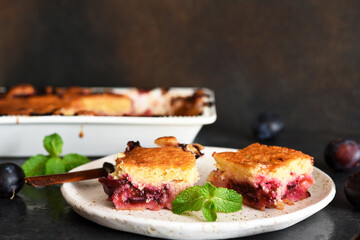 Vanilla muffin with plums and mint on a dark concrete background. Fruit pie.