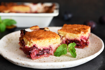 Vanilla muffin with plums and mint on a dark concrete background. Fruit pie.