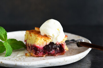 Cupcake with plums and vanilla ice cream on a dark background. Fruit pie with mint.