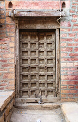 Old wooden door locked and brick wall background