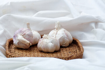 Garlic in a vintage wood plate on a white cloth background