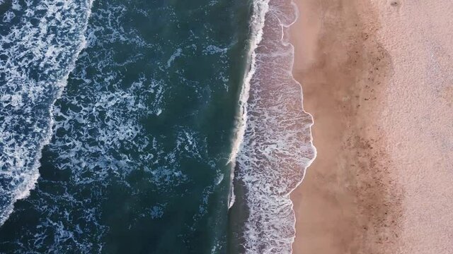 Beautiful sandy beach and foaming waves on the ocean or sea. View from above.