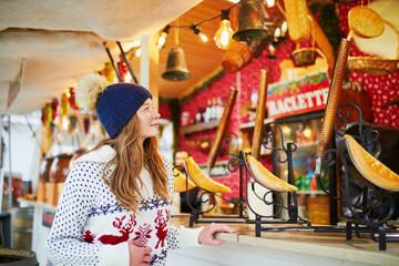 woman buying raclette (popular French and Swiss dish) on traditional Christmas market in Paris, France