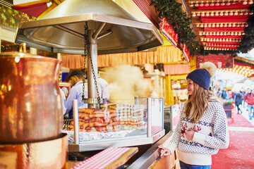 Beautiful young woman buying sausages on traditional Christmas market