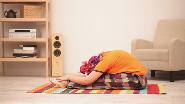 Young plus size woman with pink hair doing yoga at home. Stretching at home . High quality FullHD footage