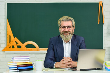 Teach and inspire. Senior teacher sit at desk. Bearded man back to school. Formal education....