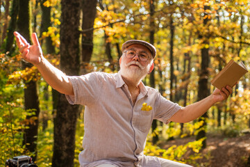 Obraz premium Hes walking encyclopedia. Elderly man hold book in nature. Pensioner read book on autumn day. Leisure for reading. Old bookworm. Travel book. Cant live without book