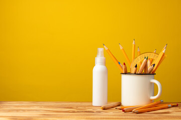 Back to school concept with stationery in cup and hand antiseptic spray