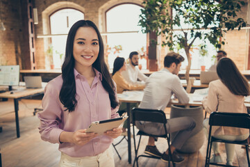 Photo of business lady young professional stand spacious big office partnership colleagues working meeting use tablet e-book analyzing anti crisis plan strategy successful team indoors