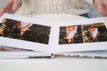 Fototapeta na wymiar close up. a woman flips through a photo book from a family pregnancy photo shoot. beautiful and convenient storage of photos. memory of an important period.