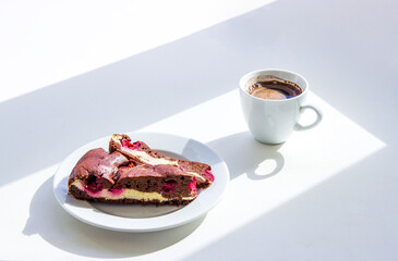 Cup of coffee and homemade brownie cake with cottage cheese and cherries on the table. Sunny morning breakfast. 