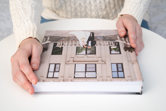 women's hands hold a wedding photo book on the table. convenient, beautiful and long-lasting storage of photos from photo sessions.