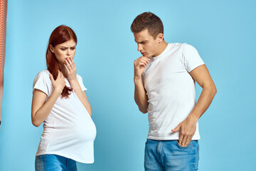 Pregnant woman in white t-shirt and man married couple waiting for baby blue background cropped view of emotions