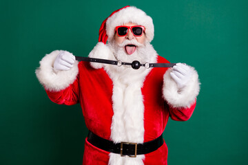 Photo of naughty crazy santa claus show tongue-out deliver x-mas christmas night midnight present woman hold leather gag wear red costume headwear isolated over green color background - obrazy, fototapety, plakaty