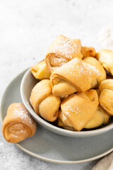 Lots of bagels. Puff pastry in a grey bowl on a light grey table. Cookies close up	