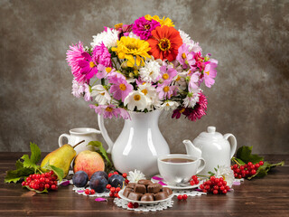Autumn still life flowers, fruits and leaves on wooden background. Tea and candy