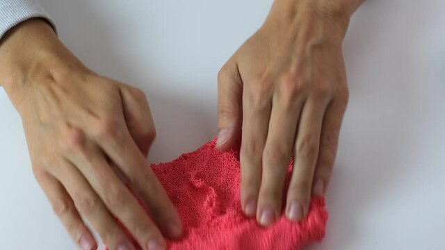 Hands crushing, squizing and crumpling pink plasticine, gum for hands with small balls inside, anti stress and relaxing game, close up