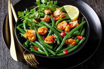 Curried salmon with green beans on a black plate