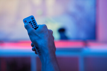 Close-up of man holding remote control during watching TV at home