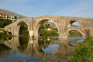 Fototapeta na wymiar old stone bridge with arches in Trebinje in the sun light with blue sky, Bosnia and Herzegovina