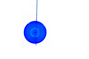 Blue Natural Plastic Round Plane Bottle Cap Pendulum Hanging On Stick Against Isolated White Background. Scientific Pendulum is used for hypnotism, reading, swinging, experiment. Copy Space For Text.