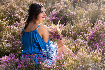 Junge glückliche Frau sitzt mit Straß im Heidekraut