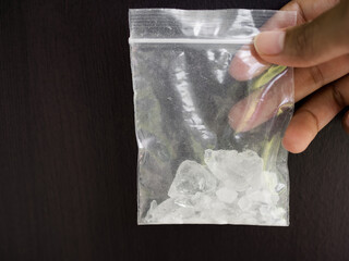 Hand holding amphetamine in plastic pack on black background. Dangerous drug. addictive substance....