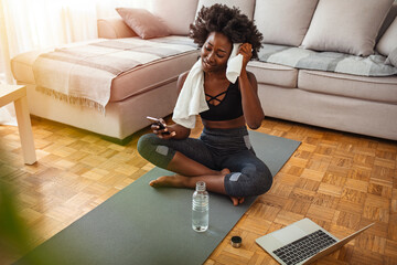 Beautiful young woman wiping sweat with a towel, exhausted after the daily training. Happy smiling...