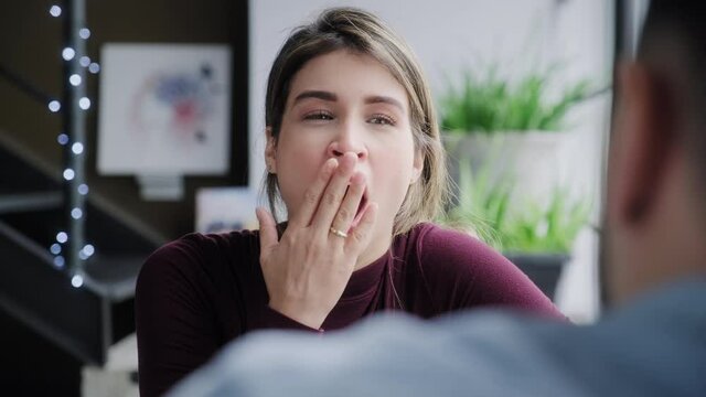 Bored woman yawning while man talks. Young people having boring conversation at home. Wife and talkative husband speaking on sofa. Married partners and relationship problems