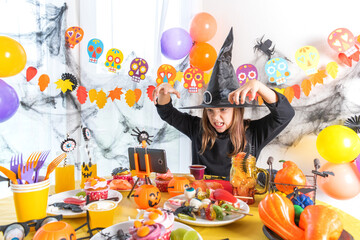 Dressed in spooky halloween costumes girl headwear having video chat on laptop with friends in decorated home.