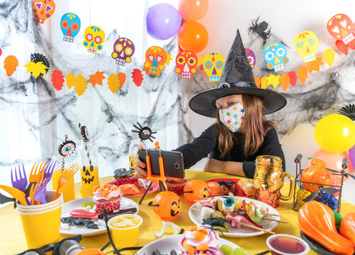 Dressed In Spooky Halloween Costumes Girl Headwear Having Video Chat On Laptop With Friends In Decorated Home.