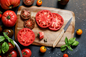 Sliced heirloom variety tomatoes with knife on chopping board. Harvest and cooking tomato sauce concept.