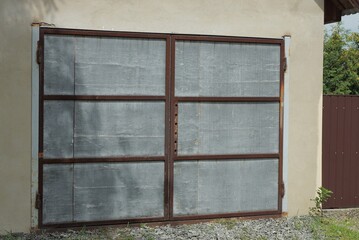 gray iron gate on a brown concrete wall of a garage on the street