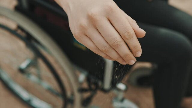 close up, hand of disabled person in the wheelchair playing with the sand on the beach. High quality 4k footage